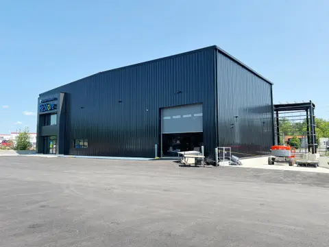 Renovated building in dark ribbed metal cladding with a new glazed entrance and overhead loading door