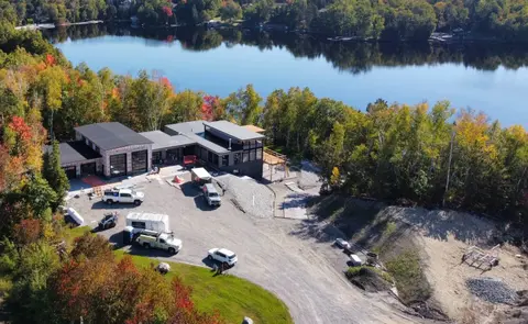 Aerial view in autumn of the finished cottage, garage and graded driveway on a wooded point above the lake