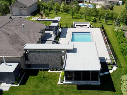 Aerial view of the house with a lounge wing, flat canopies and an in-ground pool on a green lawn