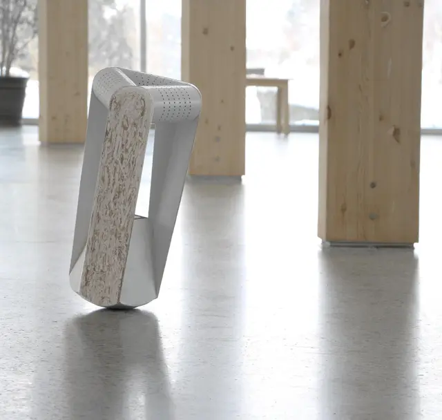 A folded white paper seat with a dark base standing on a concrete floor