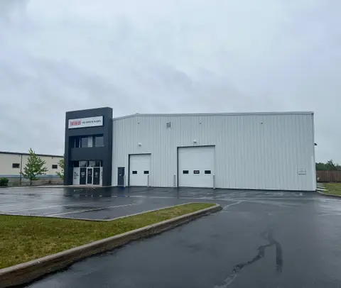 The building from the parking lot, showing the entrance volume and two overhead doors