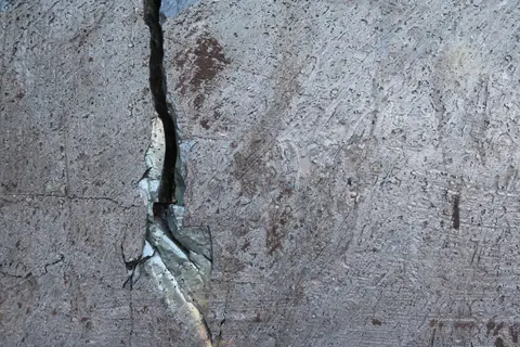 Close-up of the grey cast surface of a slag cube with a fine crack